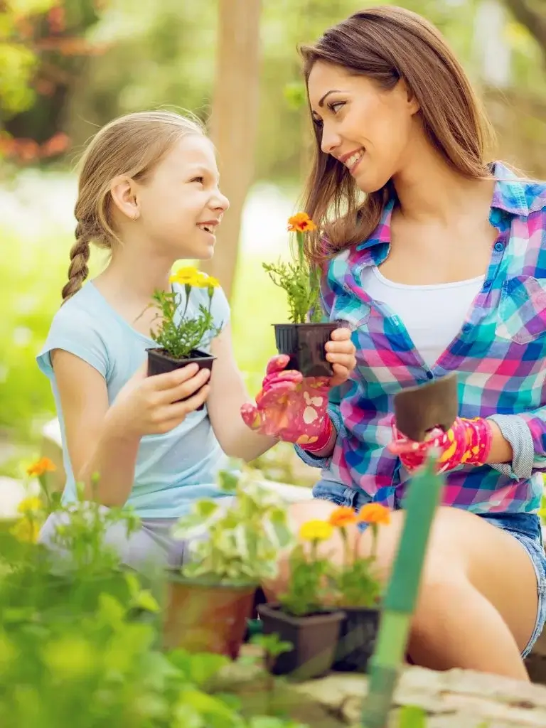 a mom and daughter holding plants and smiling at each other