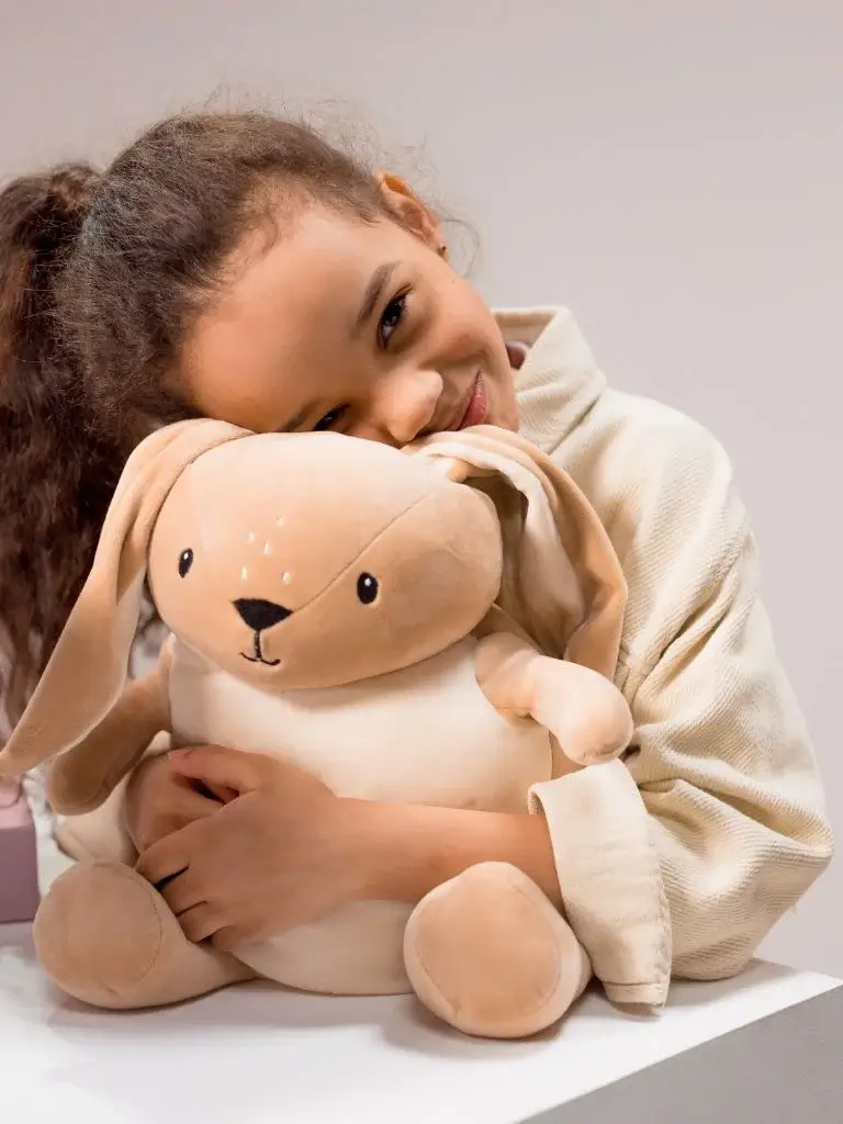 a girl hugging her stuffed rabbit toy 