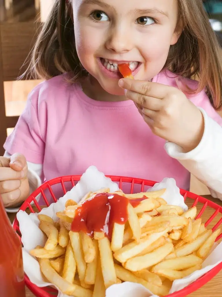 a shot of a little girl eating french fries 