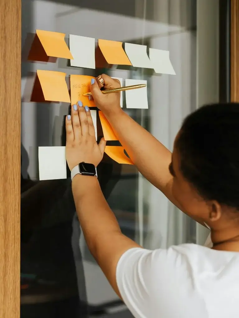 a woman pasting a sticky note on a glass window