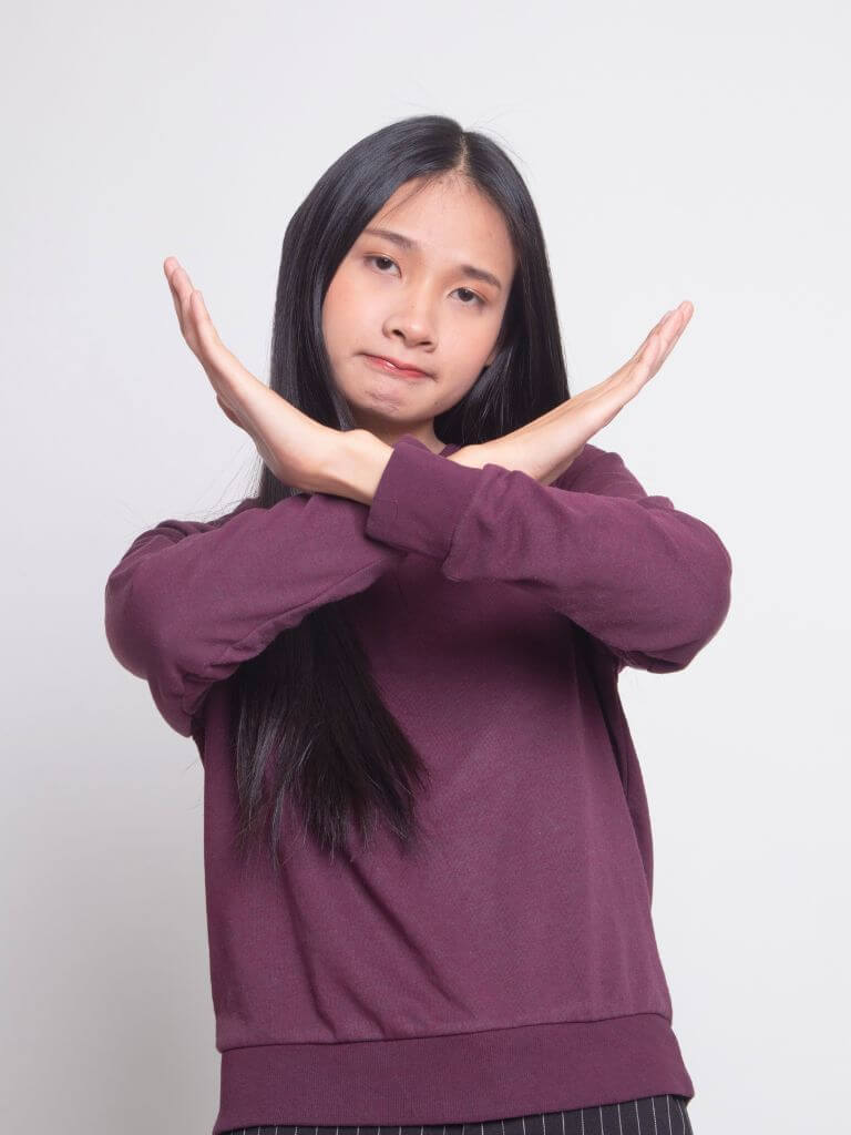 a teen making a no sign with her arms