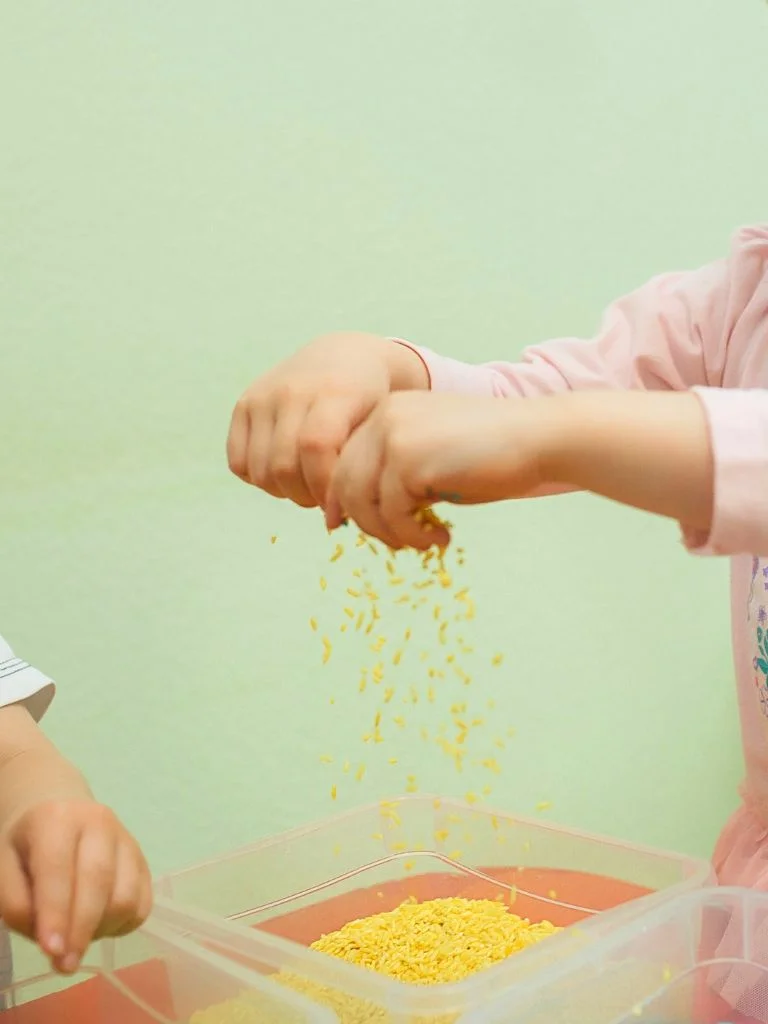 shot of a toddler's hand playing with rice bin