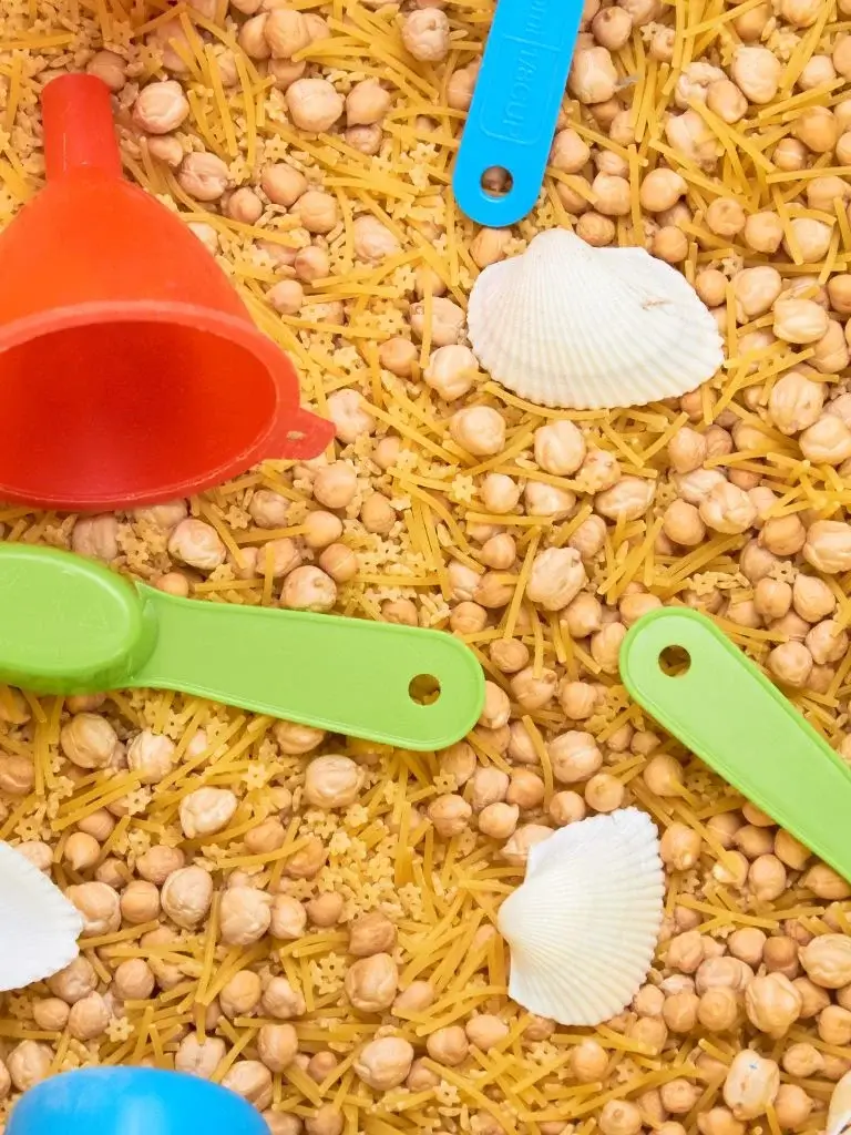 sensory bin with chickpeas and toys in it 