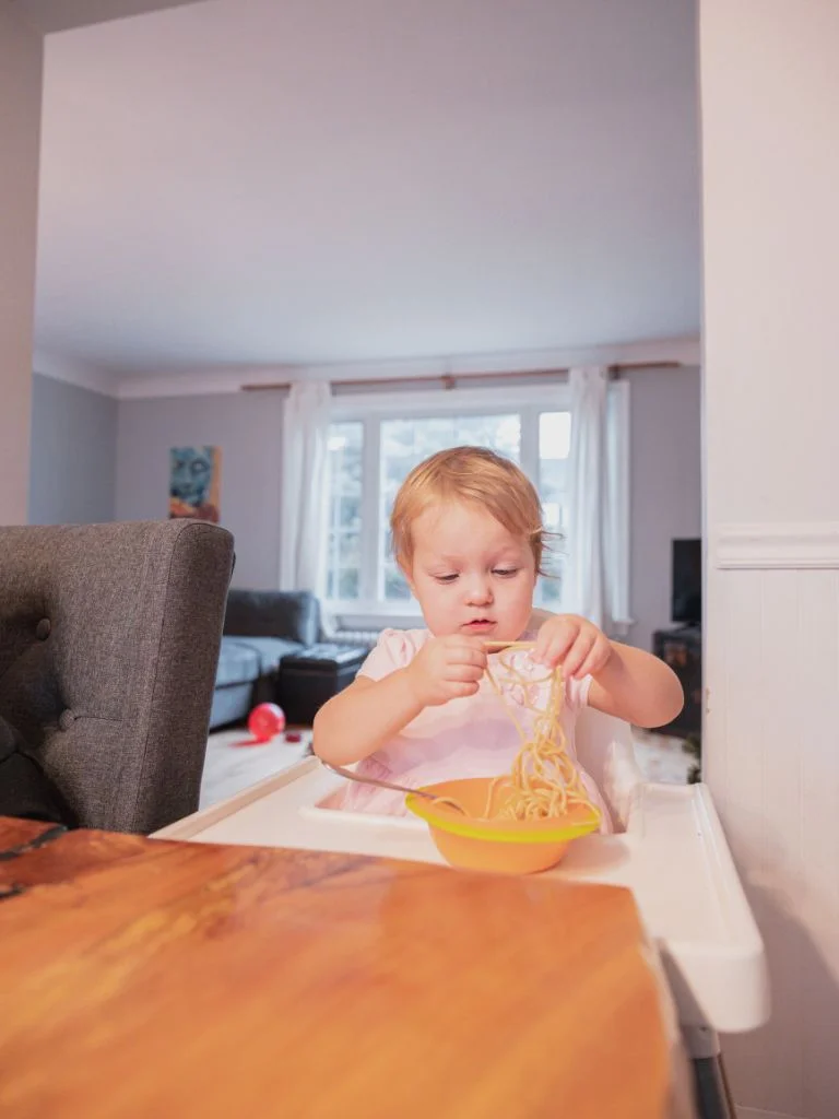 a toddler playing with spaghetti