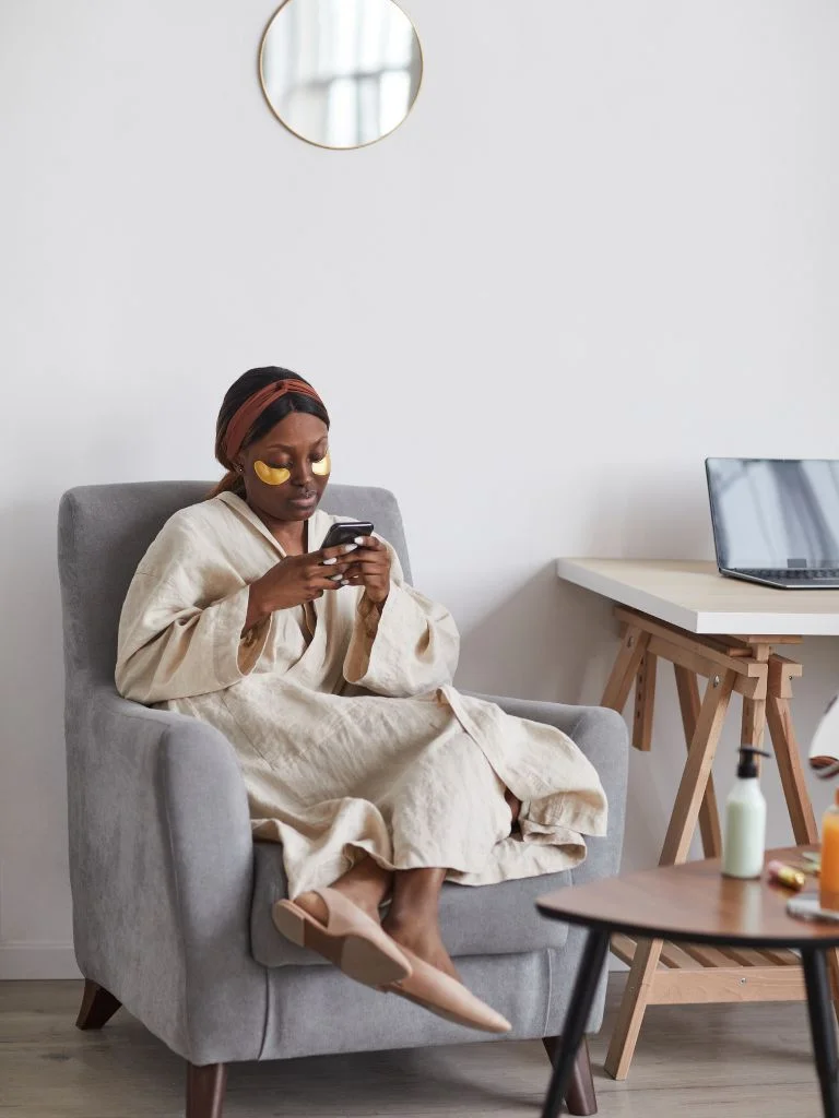 a mom taking me time by sitting on a couch and scrolling through her phone