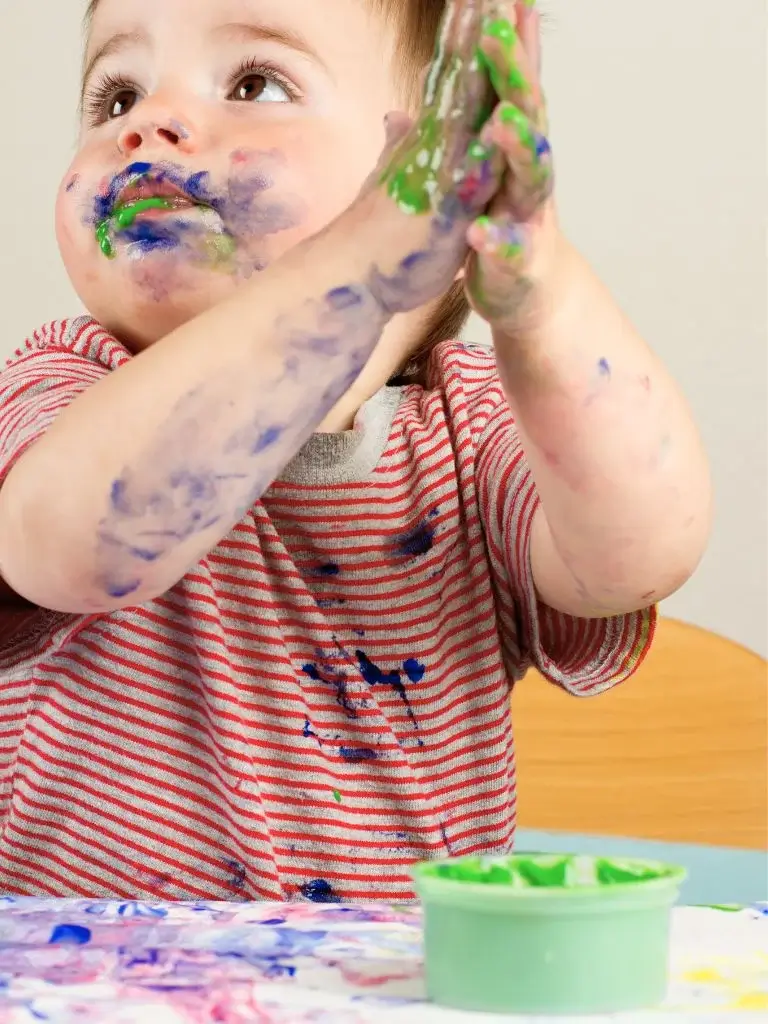 a baby playing with taste safe paint