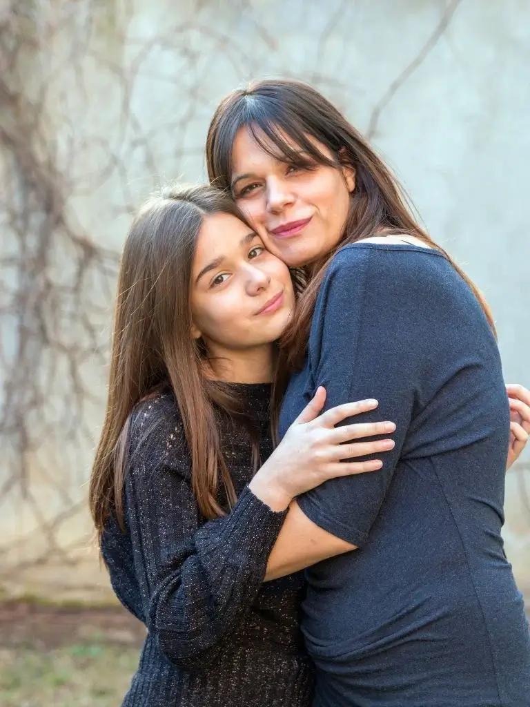 a mom hugging her teenage daughter
