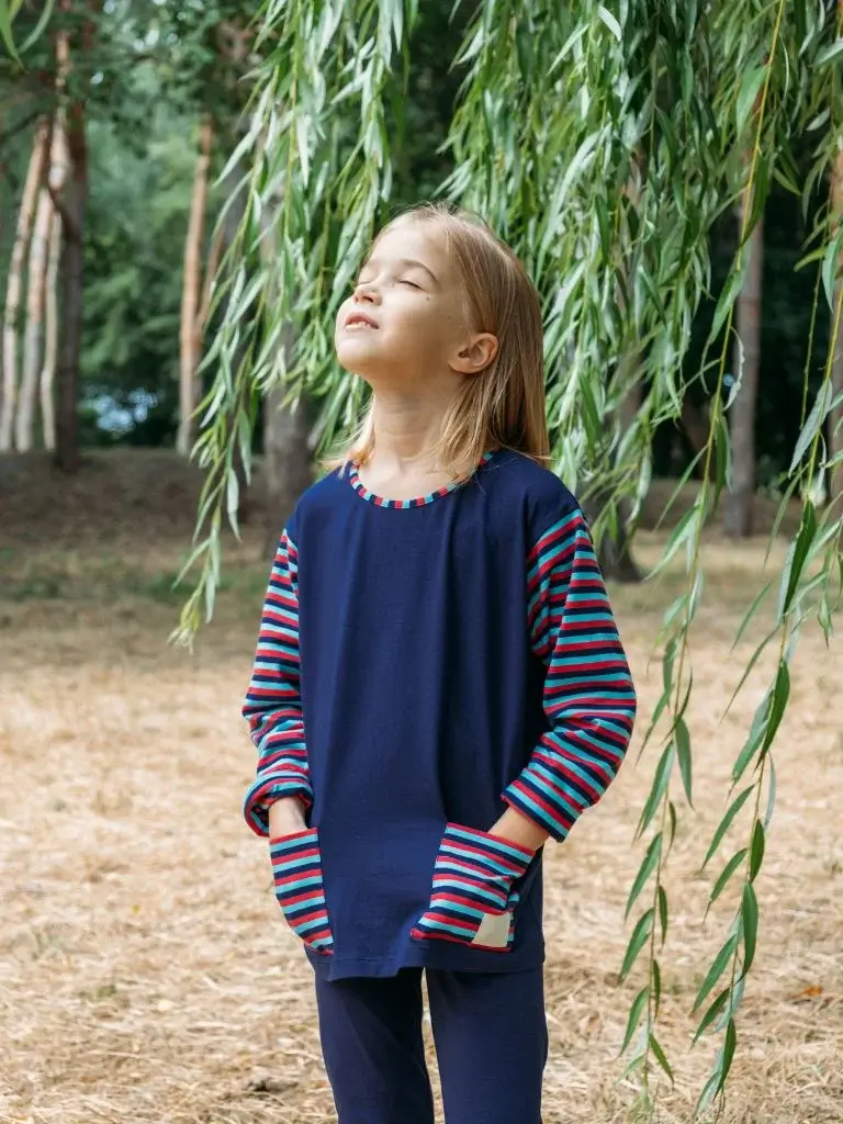 a shot of a girl standing and looking up with her eyes closed while smiling 