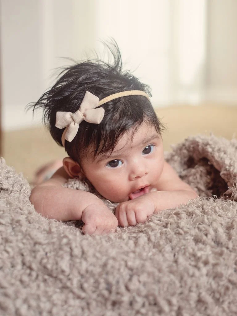 a baby lying on her belly on a carpet