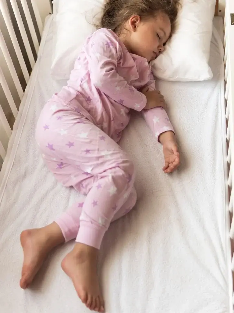 a toddler sleeping in a crib 